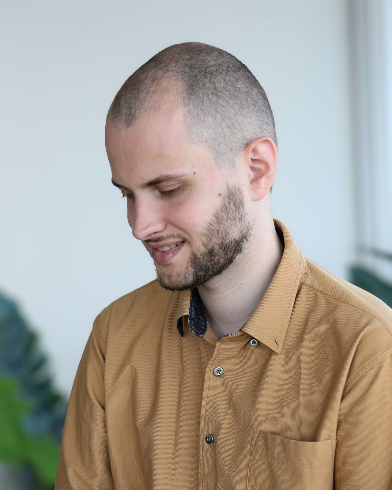 Marc de Montlivault, le regard baissé et un léger sourire, l’air attentif. Il porte une chemise couleur moutarde.